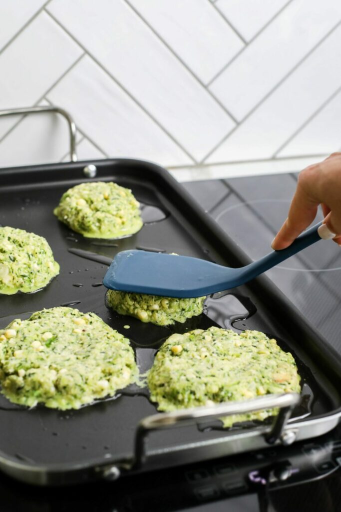 Zucchini and corn fritters being cooked on a Sharp Induction Cooktop SCH3042GB and flatted out