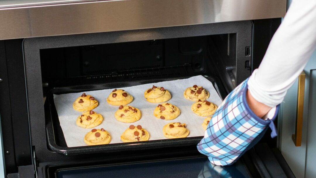 image of chocolate chip cookies being taken out of an oven
