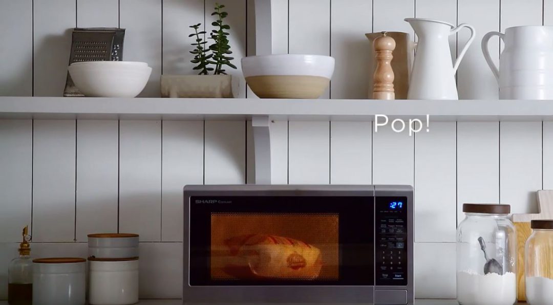 Popcorn cooking in a Sharp microwave oven in a modern kitchen design.