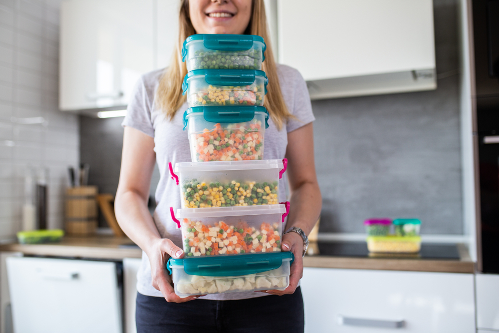 Woman in the kitchen organizing her food in plastic containers.