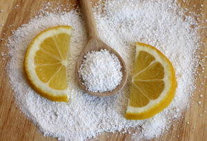 Citric acid on w wooden spoon with lemons