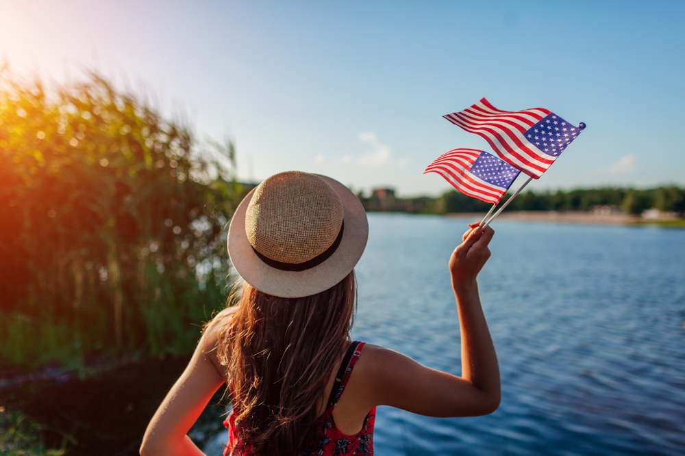 Woman standing near body of water with flag