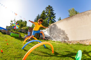 Boy jumping over obstacles in a backyard