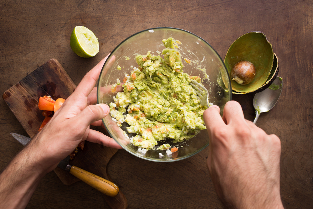 Person combining ingredients to make fresh guacamole