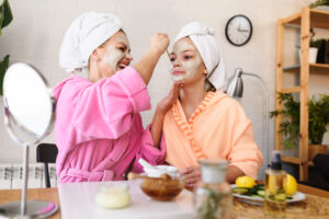 Mother and daughter in bathrobes and towels on head using natural cosmetics