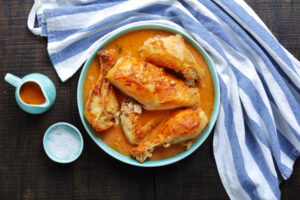 seasoned chicken in a dish on a dark table with blue dish towel