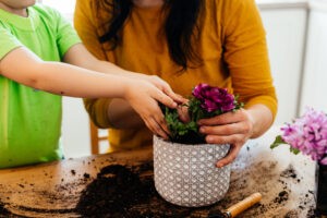 Little kid helping an adult plant a flower in a pot