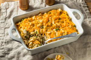tuna casserole with egg noodles and cheese in a white baking dish on a tan place mat