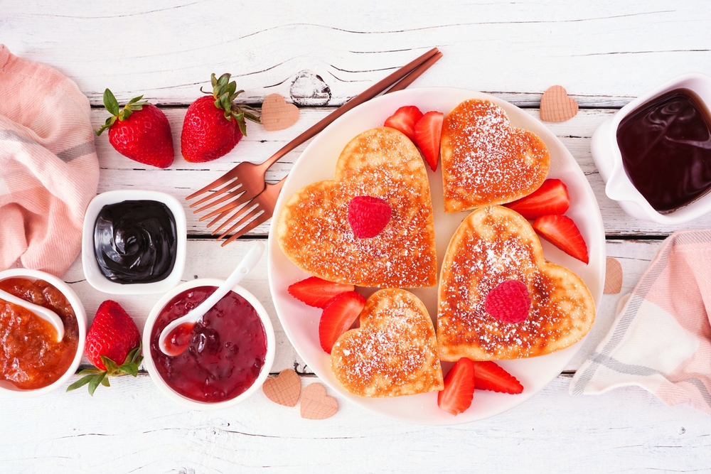 Heart shaped pancakes on a plate for a Valentine's Day breakfast spread