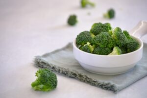Cooked broccoli in a white bowl with a fabric napkin