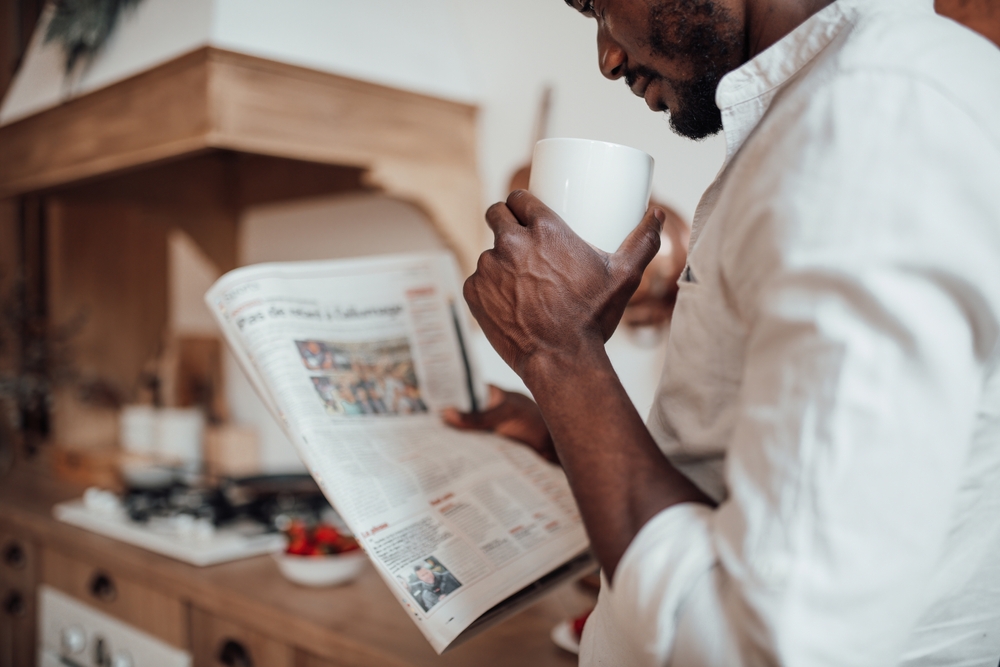 Man reading the newspaper and drinking a coffee before work
