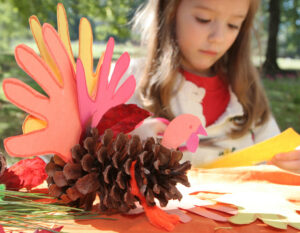 little girl making thanksgiving day craft of turkey