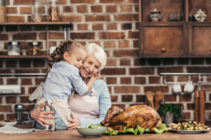 Grandmother with her Granddaughter in the kitchen with a cooked turkey on the counter