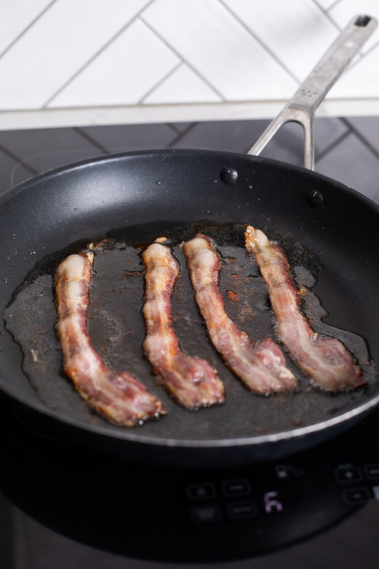 bacon cooking in a frying pan on sharp cooktop