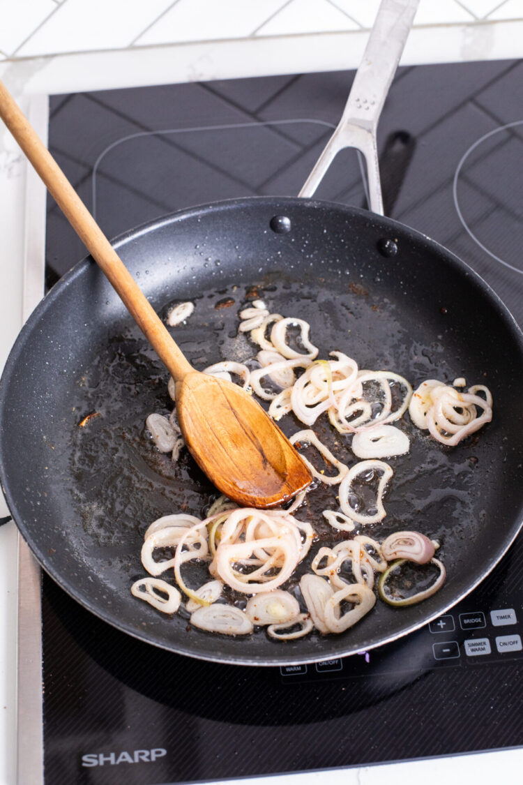 Onions being sautéed in a frying pan on a sharp cookop