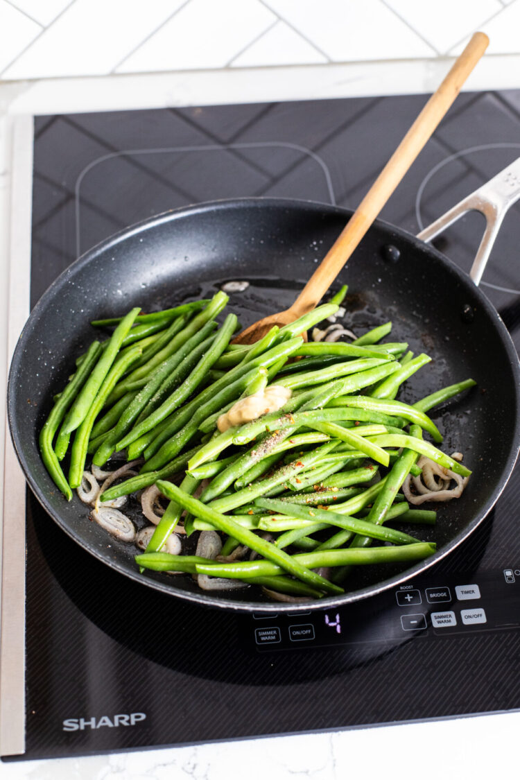 Green beans cooking in a pan on an induction cooktop