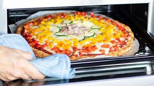 Pizza being removed from an oven